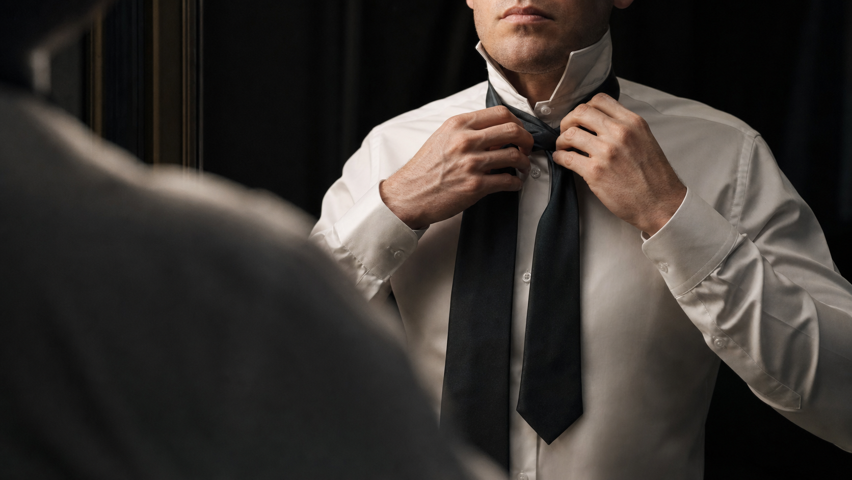 Dark silk tie draped around white collar, mirror reflection
